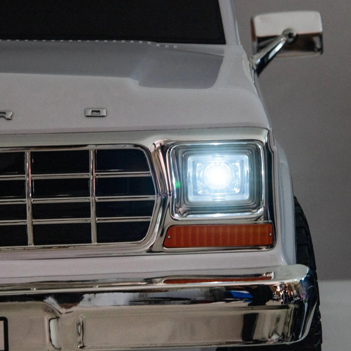 White toy car front with chrome grille and headlight illuminated, close-up view.