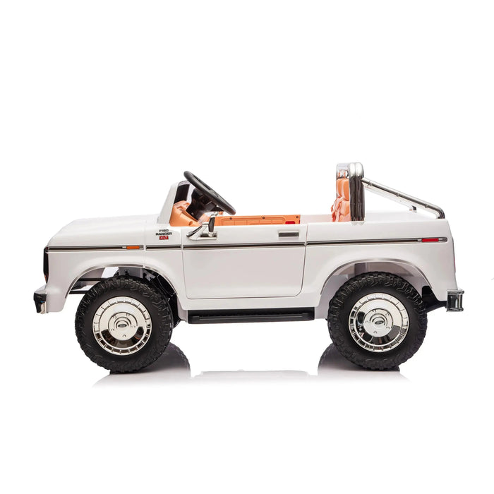 Kids ride-on white toy car with black tires and tan seats, shown in profile on white background.
