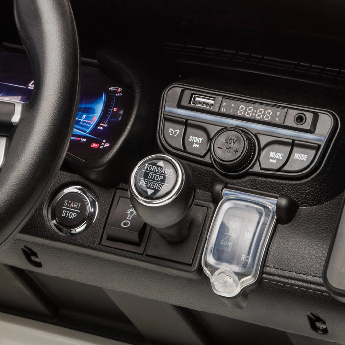 Kids ride-on car dashboard with steering wheel, gear shift, and control buttons close-up.