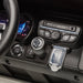 Kids ride-on car dashboard with steering wheel, gear shift, and control buttons close-up.
