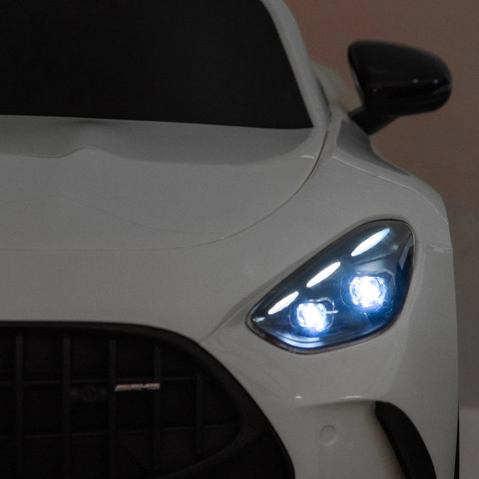 Kids ride-on car close-up of illuminated front headlights and sleek white hood.