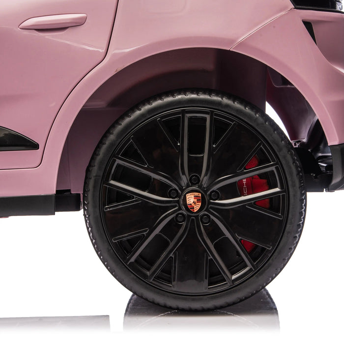 Pink Porsche toy car close-up showing black wheel and logo on white background.