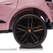 Pink Porsche toy car close-up showing black wheel and logo on white background.