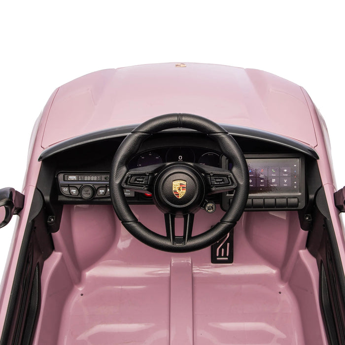 Porsche kids ride-on car dashboard close-up showing steering wheel and control panel in pink.