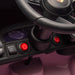 Pink ride-on toy car dashboard closeup showing steering wheel, power button, and control panel.