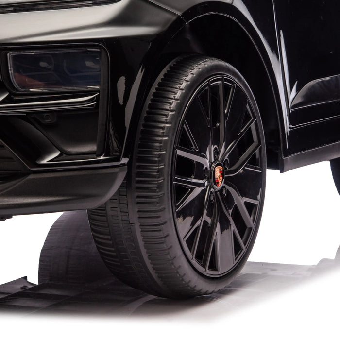Porsche Cayenne kids ride-on car close-up of black wheel and front detail on white background.