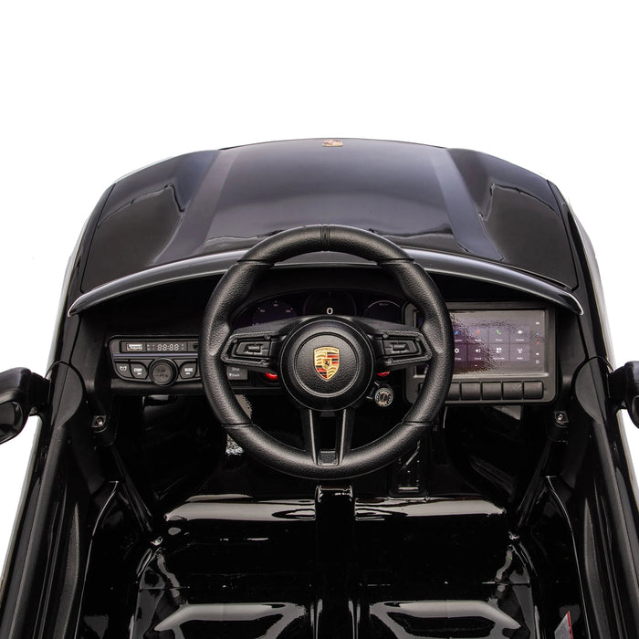 Kids Porsche ride-on car black dashboard and steering wheel interior close-up.