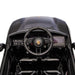 Kids Porsche ride-on car black dashboard and steering wheel interior close-up.