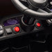 Kids ride-on car dashboard closeup showing steering wheel, control buttons, and power switch.