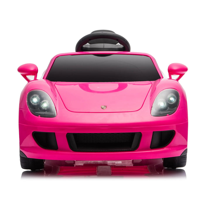 Pink ride-on toy car for kids shown from the front with headlights on against a white background.