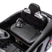 Kids ride-on car seat with seatbelt shown in a close-up, black plastic interior and steering wheel visible.