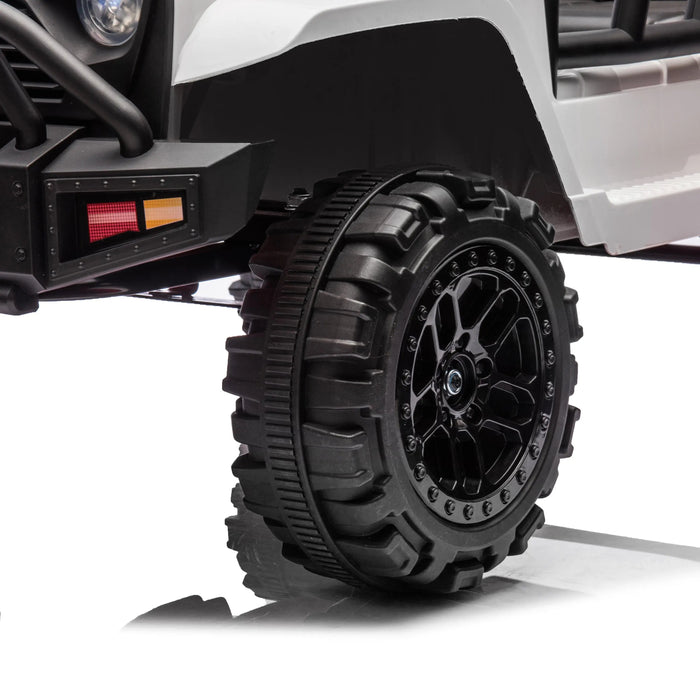 Kids ride-on toy car close-up showing rugged black wheel and front bumper detail on white background.