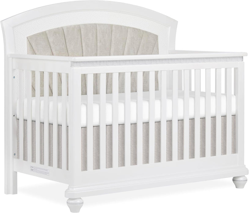 White wooden baby crib with tufted beige upholstered headboard and soft bedding
