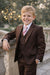 Boy's brown formal suit with vest and striped tie, smiling outdoors by stone railing