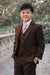 Brown teen boy suit with vest and striped tie, modeled outdoors near a stone railing.