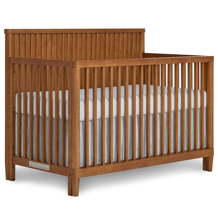Natural wood baby crib with slatted sides and white mattress, nursery furniture