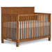 Natural wood baby crib with slatted sides and white mattress, nursery furniture