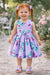 Roses & Butterflies Silky Dress lilac shown on a smiling young girl outdoors in a garden.