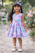 Roses Butterflies Silky Dress lilac shown on a young girl standing outdoors in a garden setting.