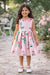 Girls pink silky dress with roses and butterflies, worn by a child outdoors in a garden setting.