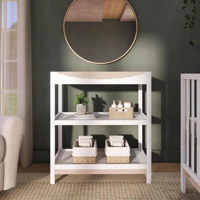 White baby changing table with shelves, storage baskets, and nursery decor in a modern room