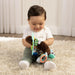 Infantino Textured Multi Ball Buddy toy held by smiling baby sitting on a soft carpet.