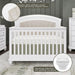White baby crib with velvet upholstered headboard, shimmering finish, and sparkling trim in a modern nursery.