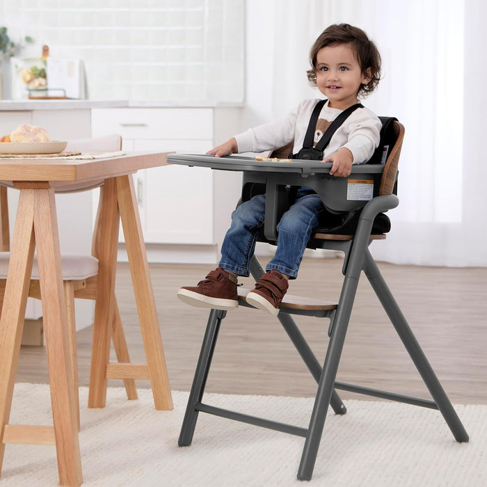 Toddler sitting in a modern high chair with safety harness in a bright kitchen