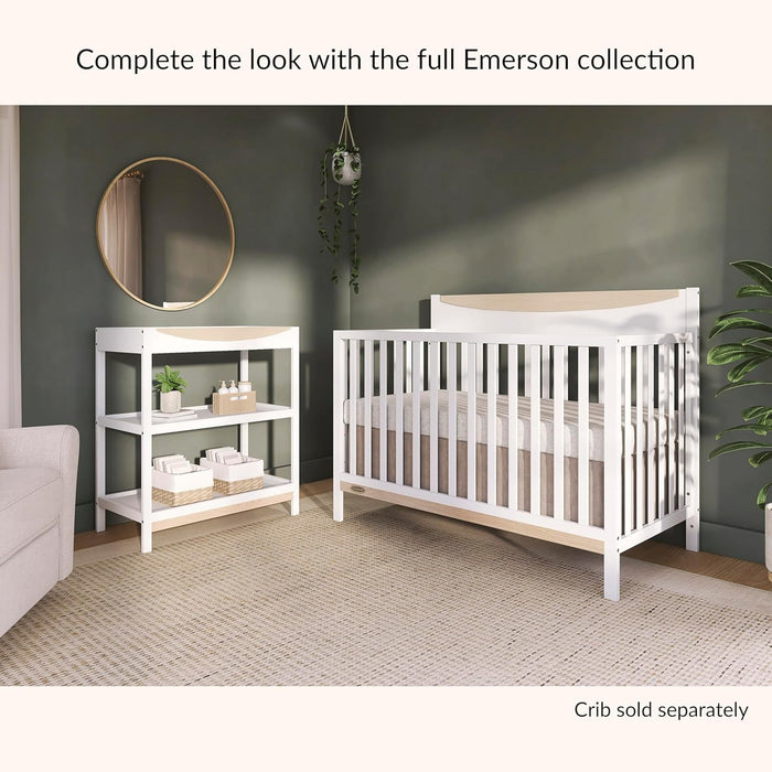 Modern nursery with white crib and changing table, neutral decor, and green accent wall.