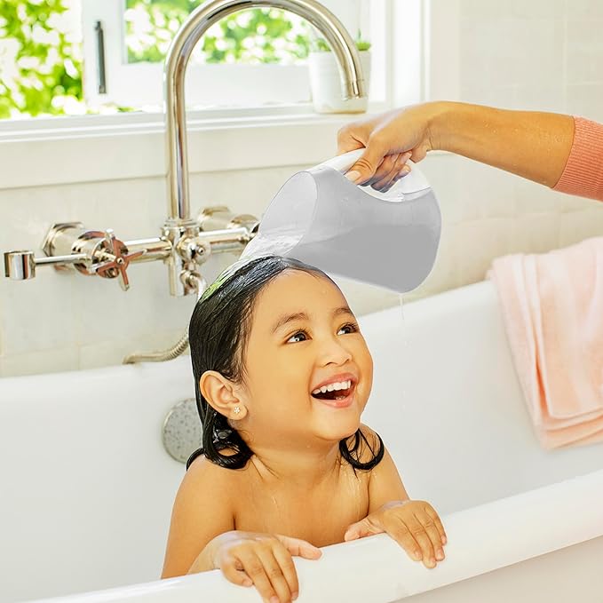 Smiling child in bathtub having hair rinsed with a bath rinser cup, kid bath time product