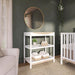 White nursery changing table with storage baskets and baby essentials in modern baby room