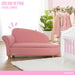 Pink chaise lounge for kids in a nursery room with dresses, crib, and plant