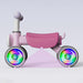 Pink toddler balance bike with LED light-up wheels against a plain light background.