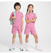 Nike kids' pink t-shirt and shorts set modeled by two children standing against a white background.