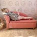 Smiling girl in plaid dress and pink tights lounging on pink kids' sofa in a nursery