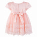Peach baby dress with lace floral hem and a bow at the back, displayed on a white background.