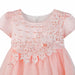 Peach baby dress with floral lace applique and pearl accents shown on white background.