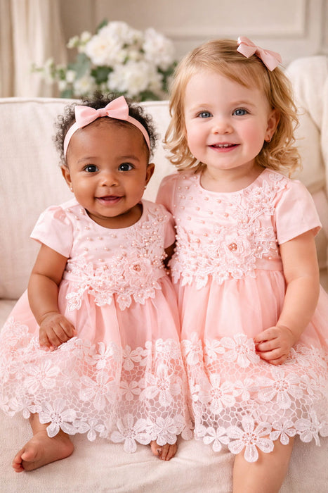 Peach lace baby dresses with floral embroidery, shown on two toddlers sitting indoors on a sofa.