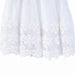White girls' dress with floral lace hem detail shown close up against a white background.