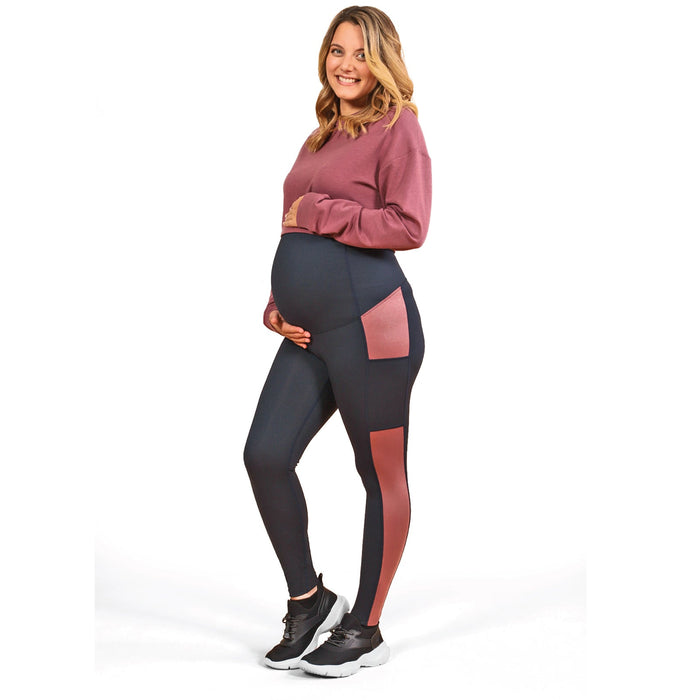 Athena Duo maternity leggings shown on a pregnant woman standing and smiling on a white background.