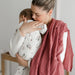Mother cuddling baby in white floral bamboo sleeper pajamas, pink muslin blanket over shoulder