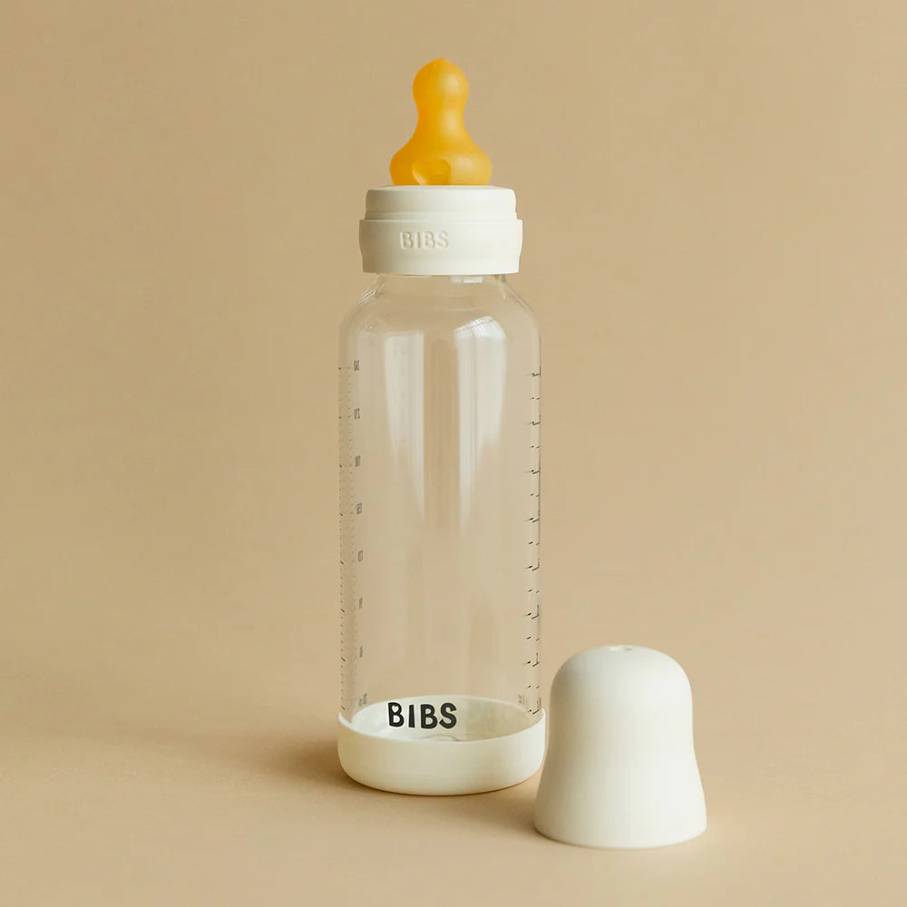 BIBS baby glass bottle with yellow nipple and white cap on a neutral background.