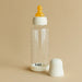 BIBS baby glass bottle with yellow nipple and white cap on a neutral background.
