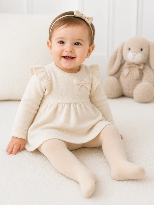 Bellissima ecru white baby tights shown on a smiling baby sitting on a soft white blanket indoors.