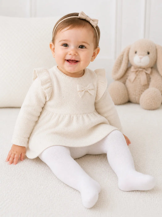 Bellissima ecru white baby tights worn by a smiling baby sitting on a soft cream blanket.