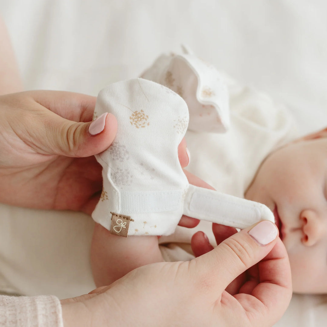 Baby's Goumi Dandelion anti-scratch Mitts - mom putting on the mitt on babys hand with the hook-and-loop adjustable strap