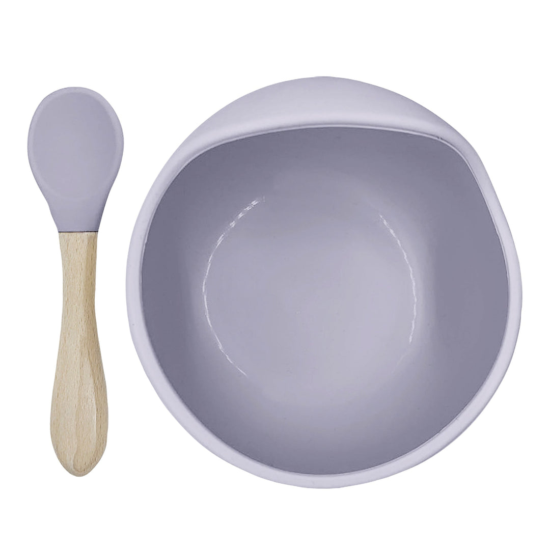 Lilac silicone baby feeding bowl and matching spoon with wood handle on white background