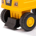 CAT toy dump truck closeup showing yellow plastic body and black wheels on a white background.