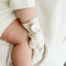 Close-up on baby's hand wearing the Goumi anti-scratch mitts Terrazzo with the chubby leg next to it - Goldtex