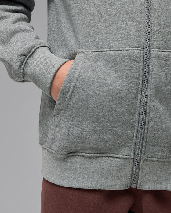 Grey fleece zip hoodie with front pocket, shown worn by a person with hand in pocket.